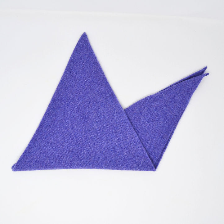 A folded Scarlet Knitwear brand lambswool triangle scarf in dark heather (a bright purple).