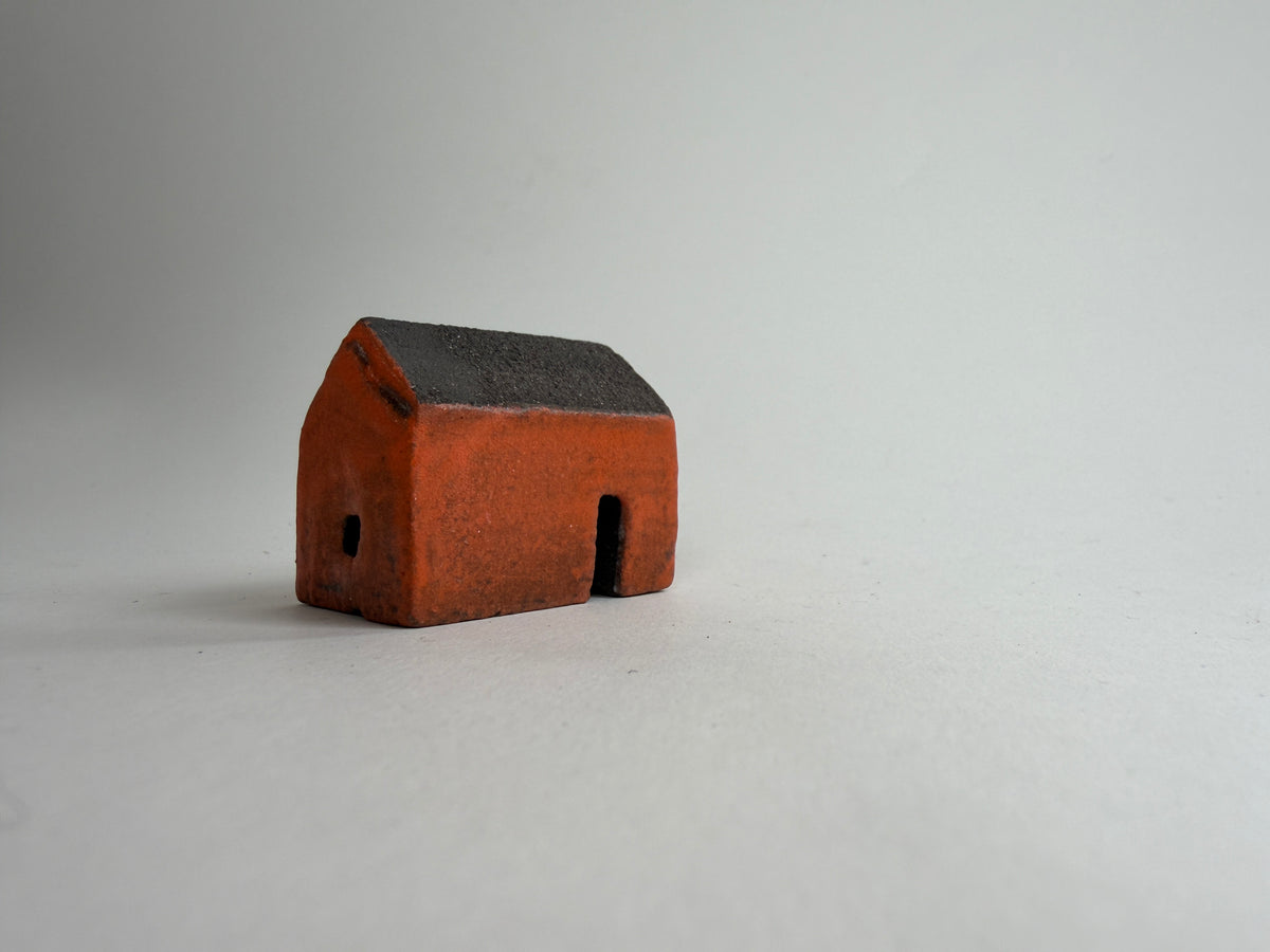 A small decorative ceramic house ornament shown against a plain light gray background.