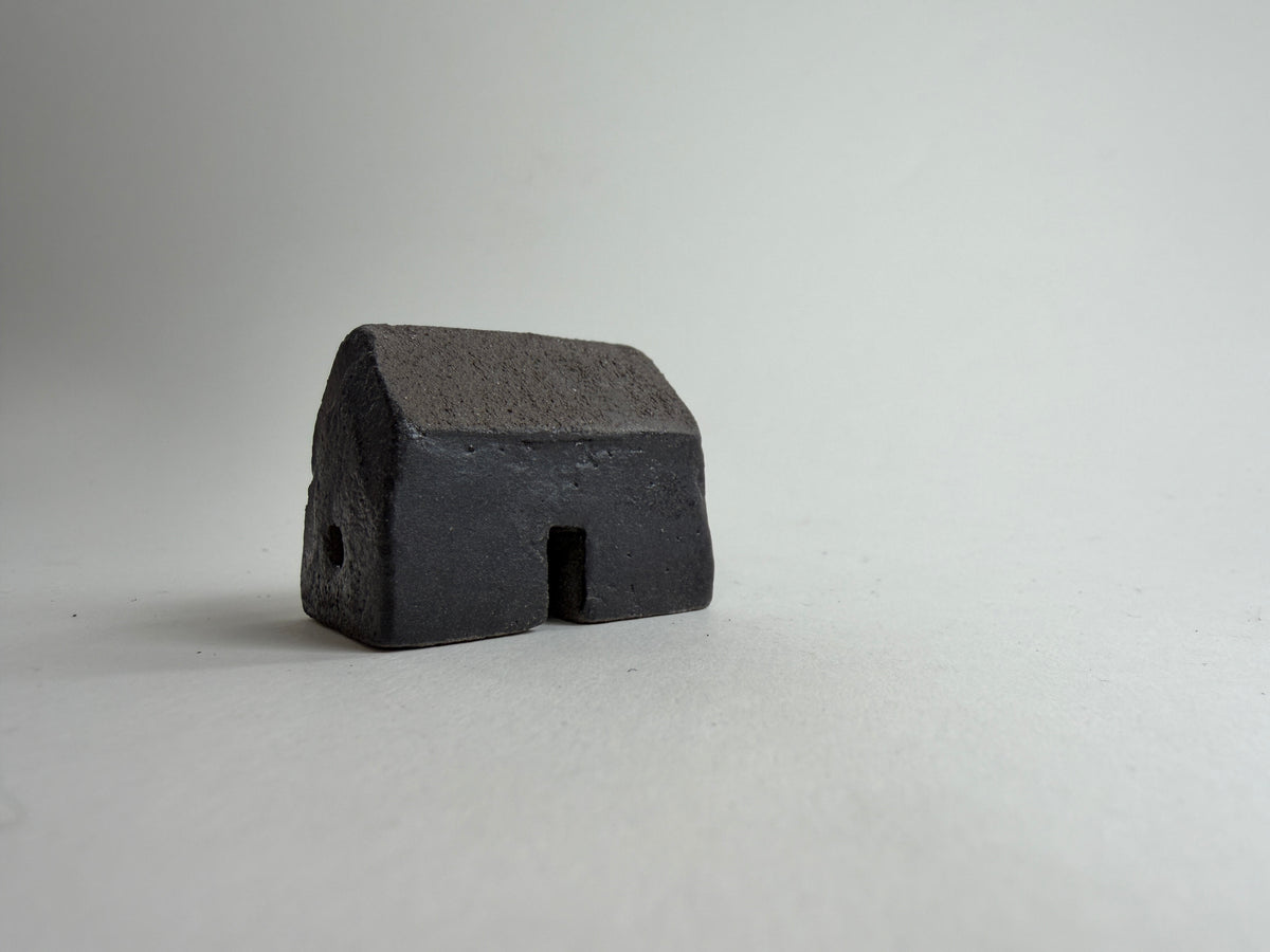 A small decorative ceramic house ornament shown against a plain light gray background.