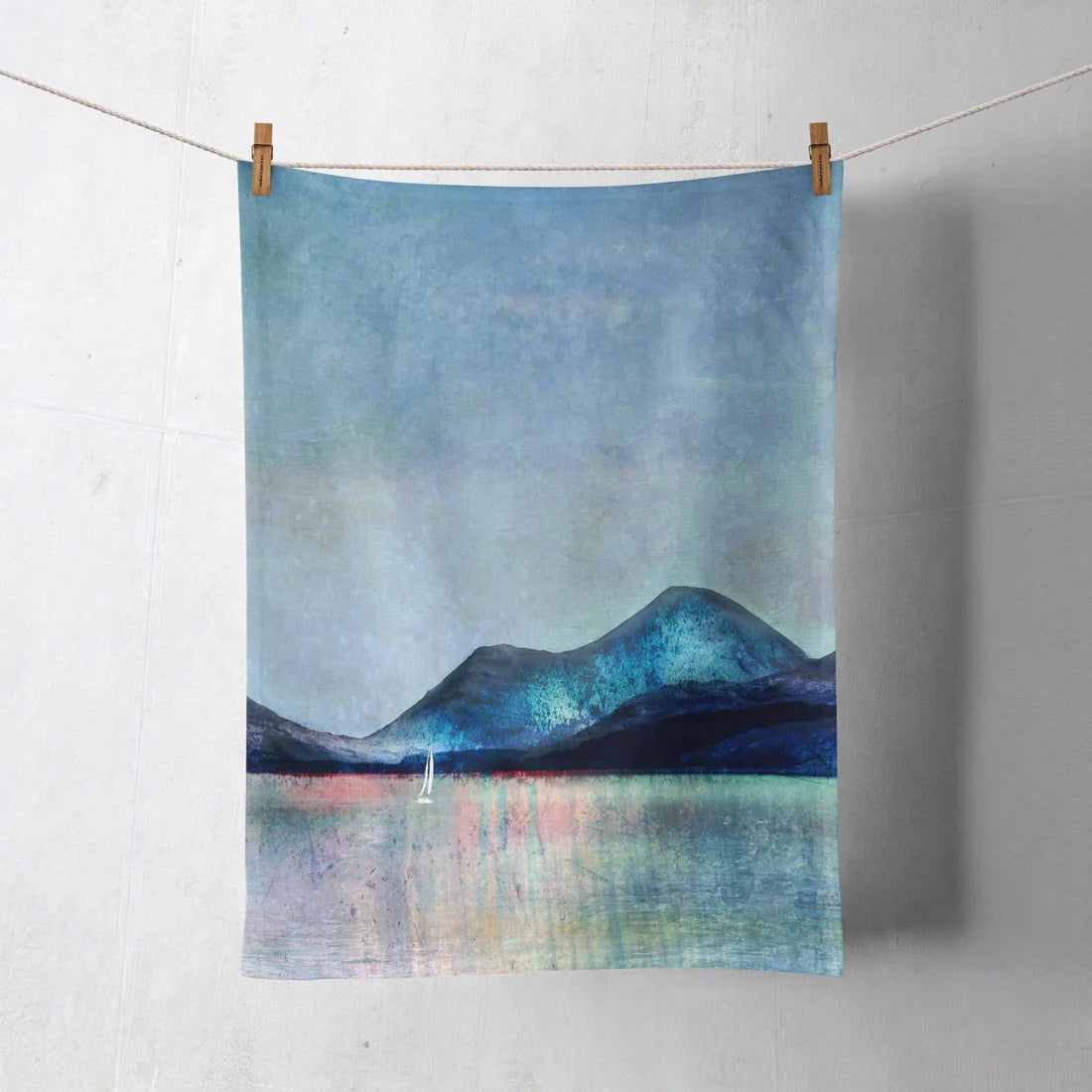 100% cotton tea towel pegged on a line printed with colourful landscape artwork by Cath Waters inspired by the Isle of Mull.