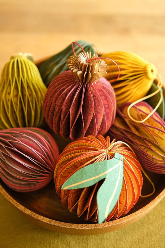 A bowl full of colourful fruit-shaped eco-friendly recycled paper honeycomb decorations.
