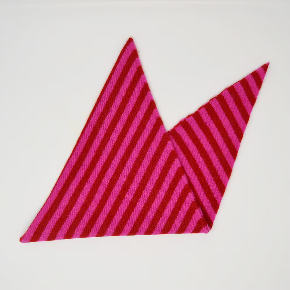 A folded Scarlet Knitwear brand lambswool triangle scarf with a pink and ruby stripe design.