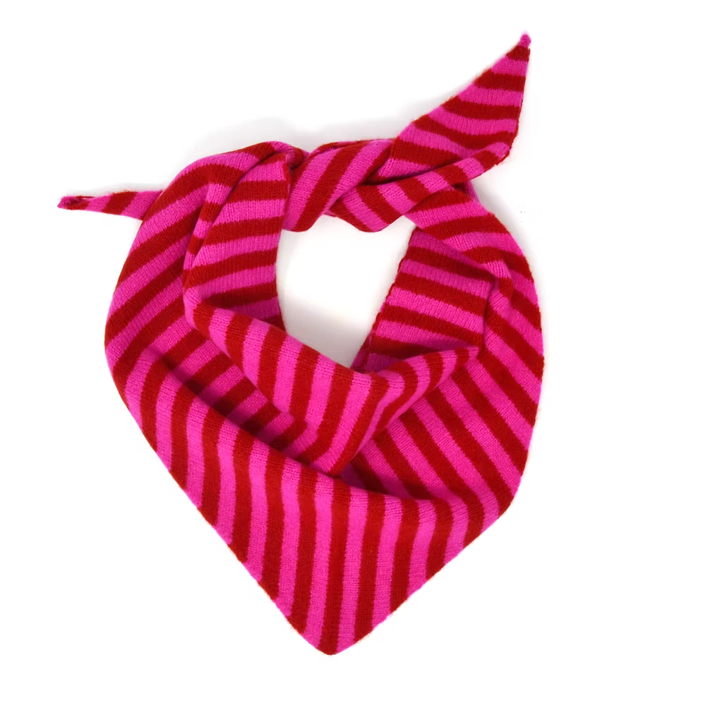 A Scarlet Knitwear brand lambswool triangle scarf with a pink and ruby stripe design, arranged as it would be worn.