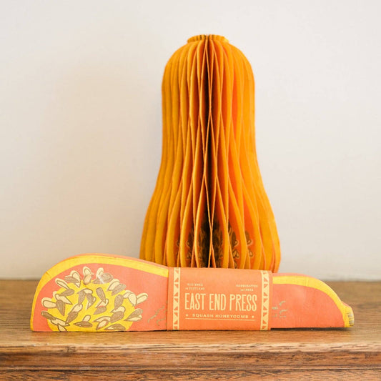 A packaged honeycomb squash decoration on a shelf with an opened decoration behind.