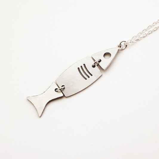 A silver fish-shaped pendant necklace on a matching chain, photographed on a clean white background.