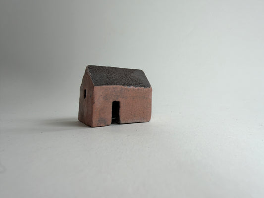 A small decorative ceramic house ornament shown against a plain light gray background.