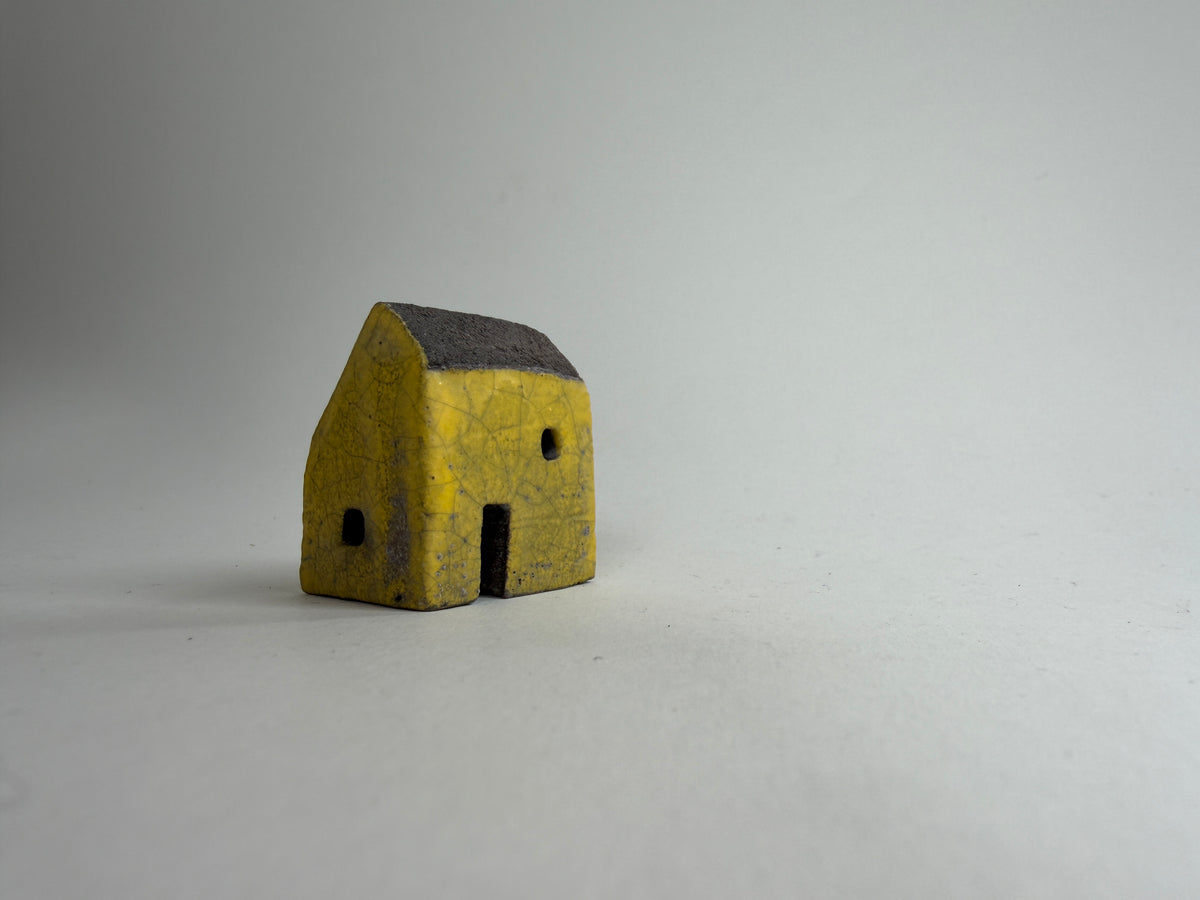 A small decorative ceramic house ornament shown against a plain light gray background.