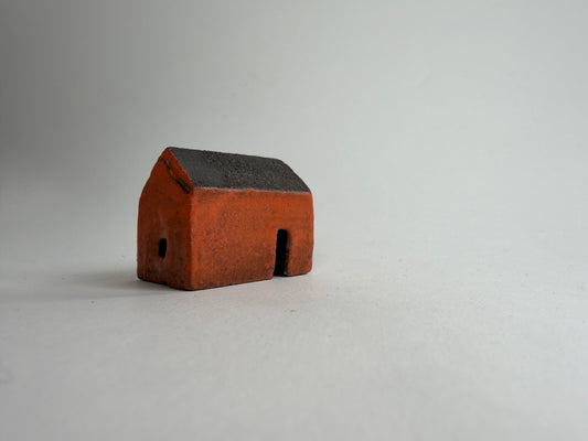 A small decorative ceramic house ornament shown against a plain light gray background.