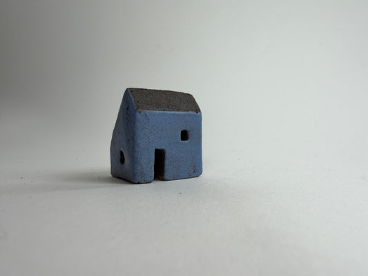 A small decorative ceramic house ornament shown against a plain light gray background.