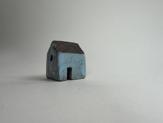 A small decorative ceramic house ornament shown against a plain light gray background.