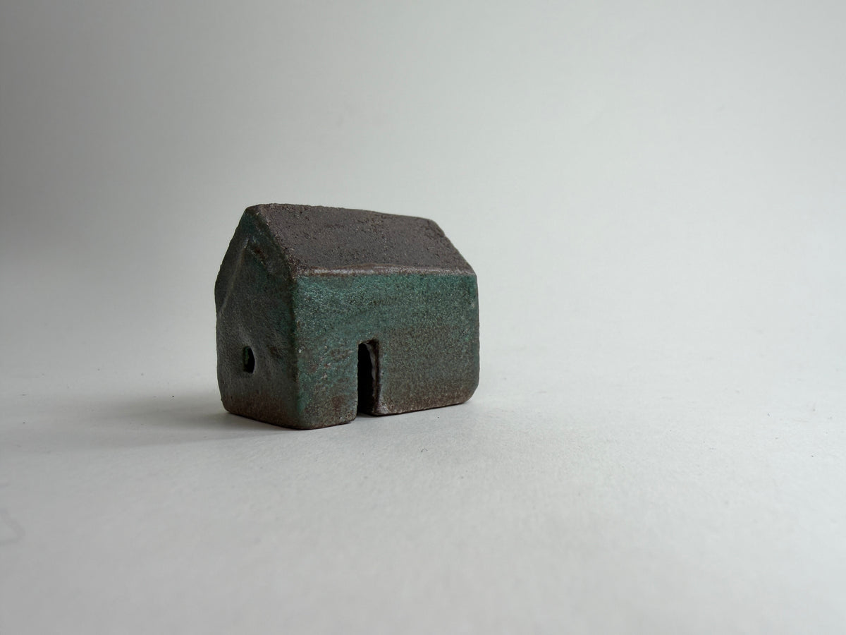 A small decorative ceramic house ornament shown against a plain light gray background.