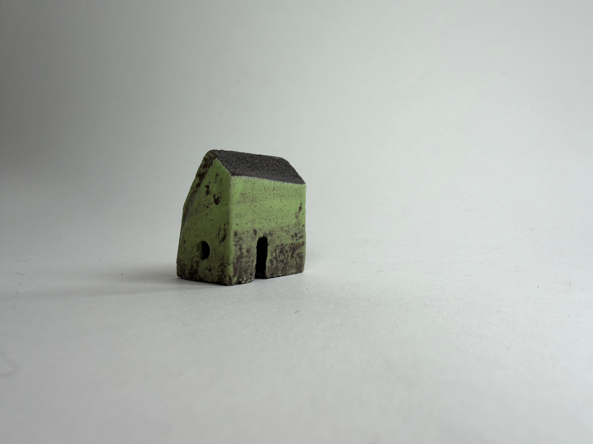 A small decorative ceramic house ornament shown against a plain light gray background.