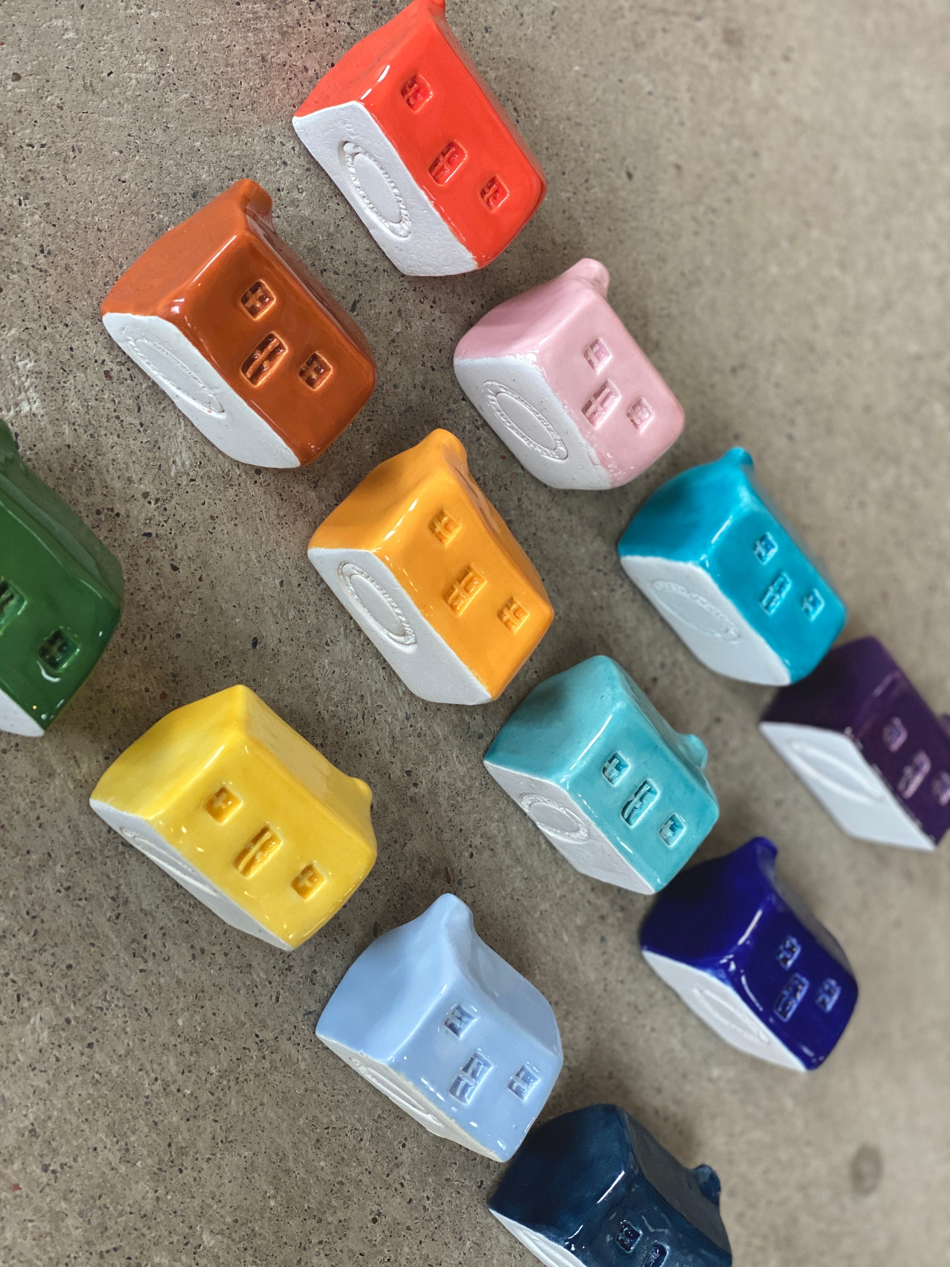 A rainbow of colourful handmade ceramic bothies showing the stamped bottoms.