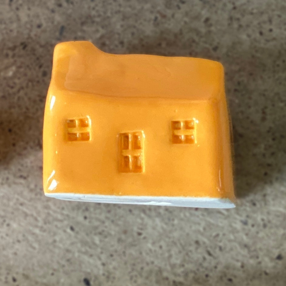 A handmade ceramic bothy with a bright orange glaze.