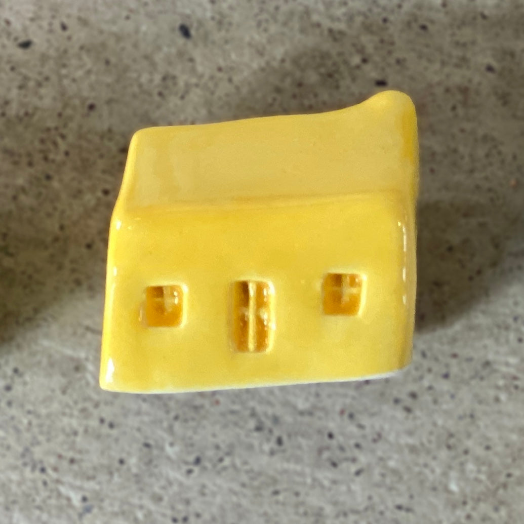 A handmade ceramic bothy with a bright yellow glaze.