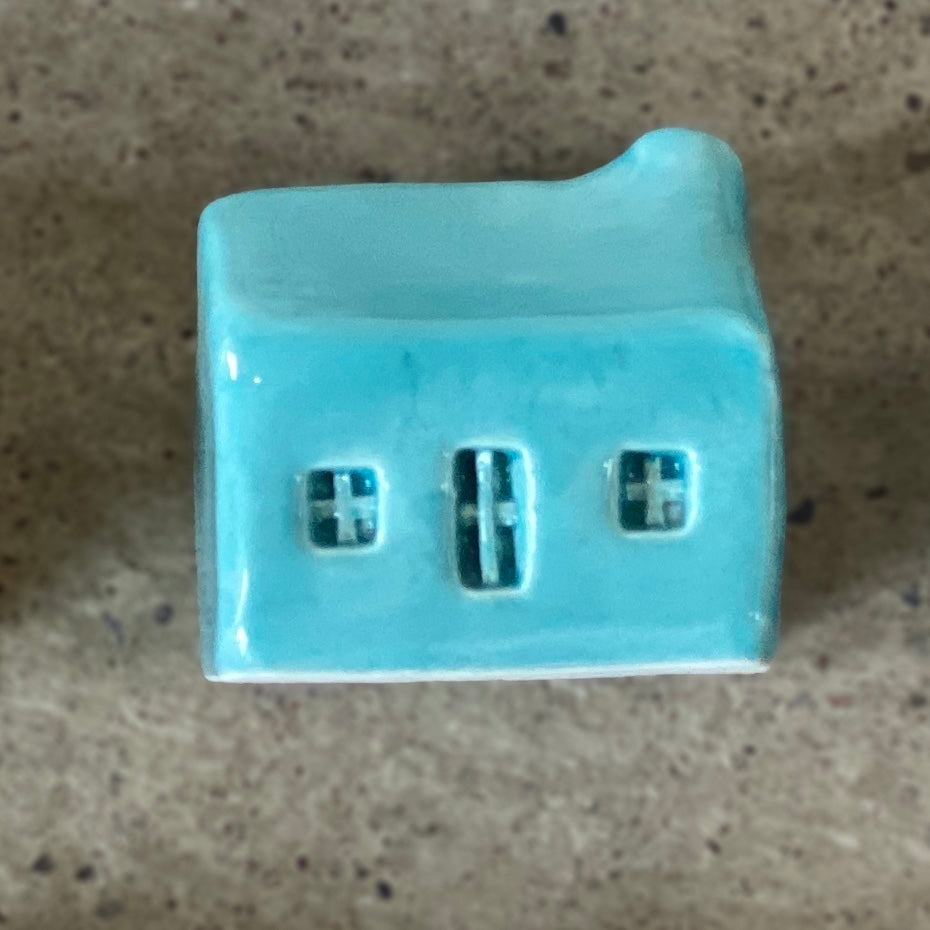 A handmade ceramic bothy with a bright turquoise glaze.
