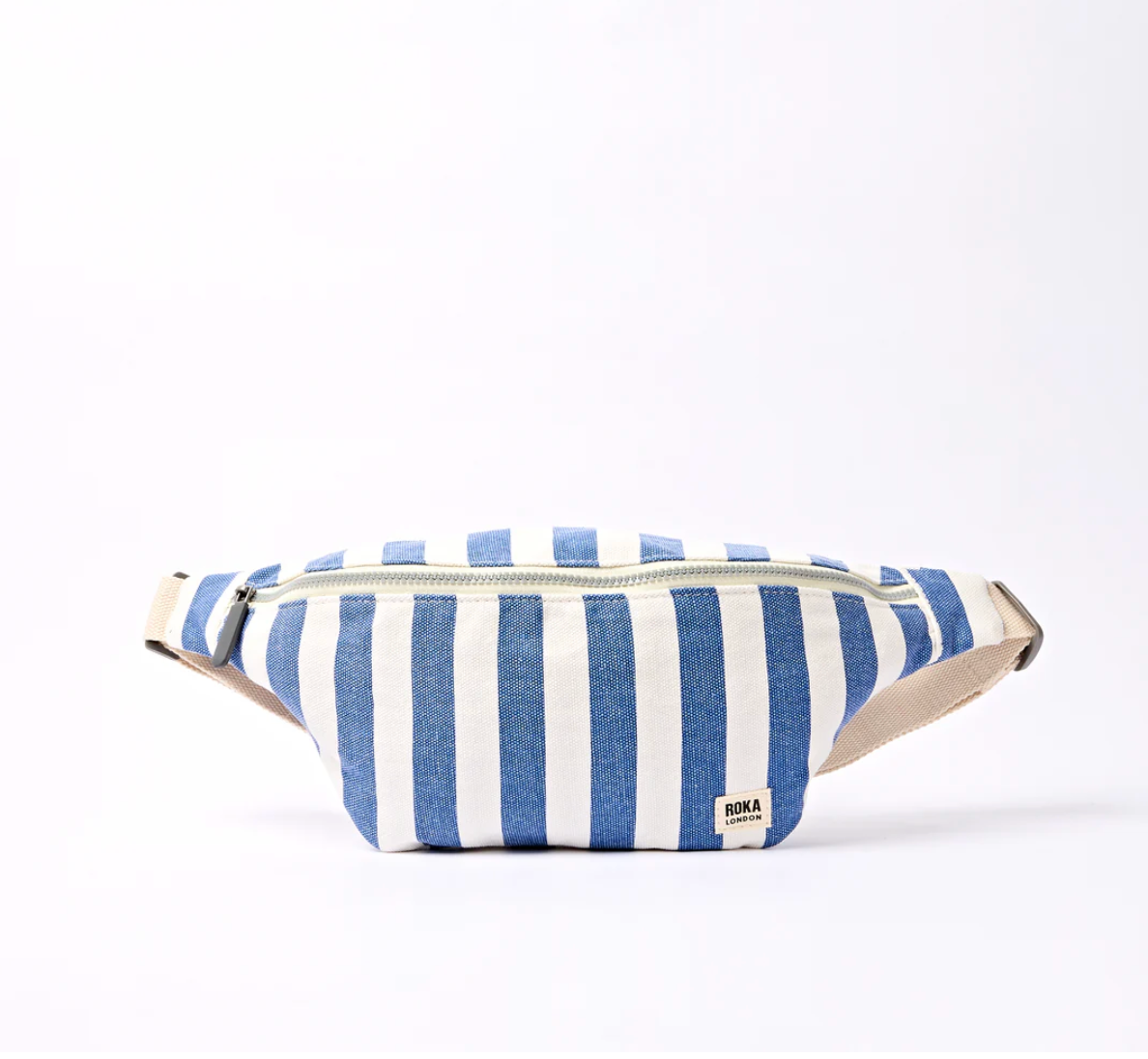 A blue and white striped canvas sling bag with a beige adjustable strap and a small 'ROKA' brand label on the front, set against a plain white background.