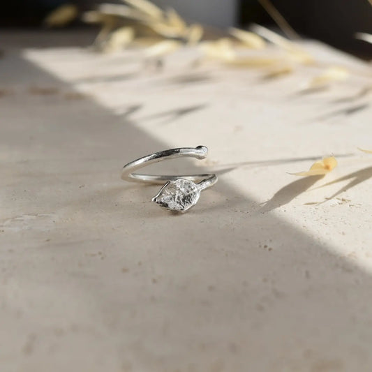 A recycled sterling silver molten finish adjustable open leaf ring on a neutral background.