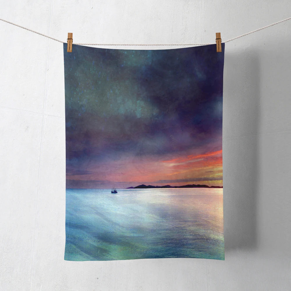 100% cotton tea towel pegged on a line printed with colourful landscape artwork by Cath Waters inspired by Fishing the Little Minch.